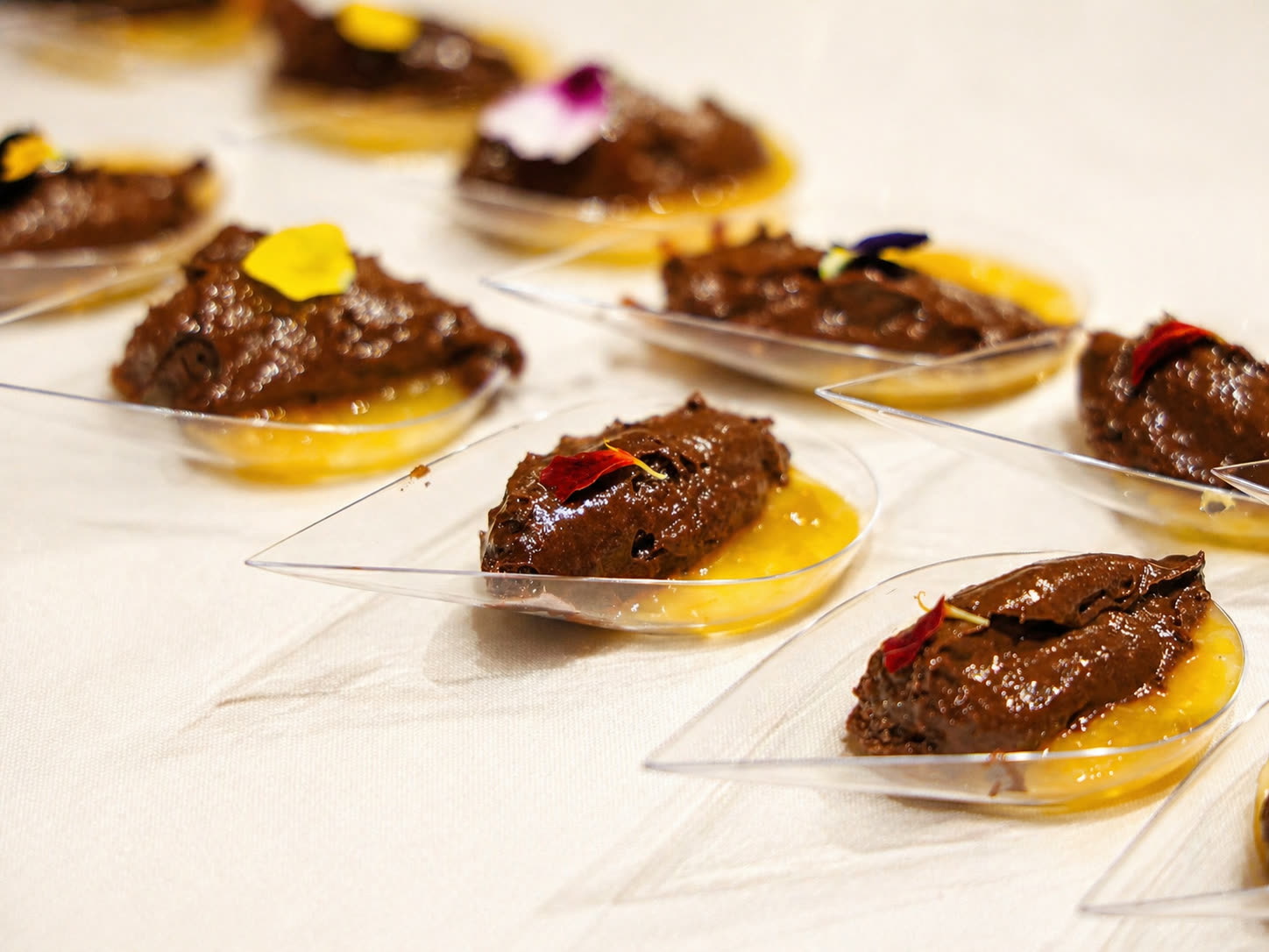Colheres de mousse de chocolate com coulis de maracujá e flores comestíveis