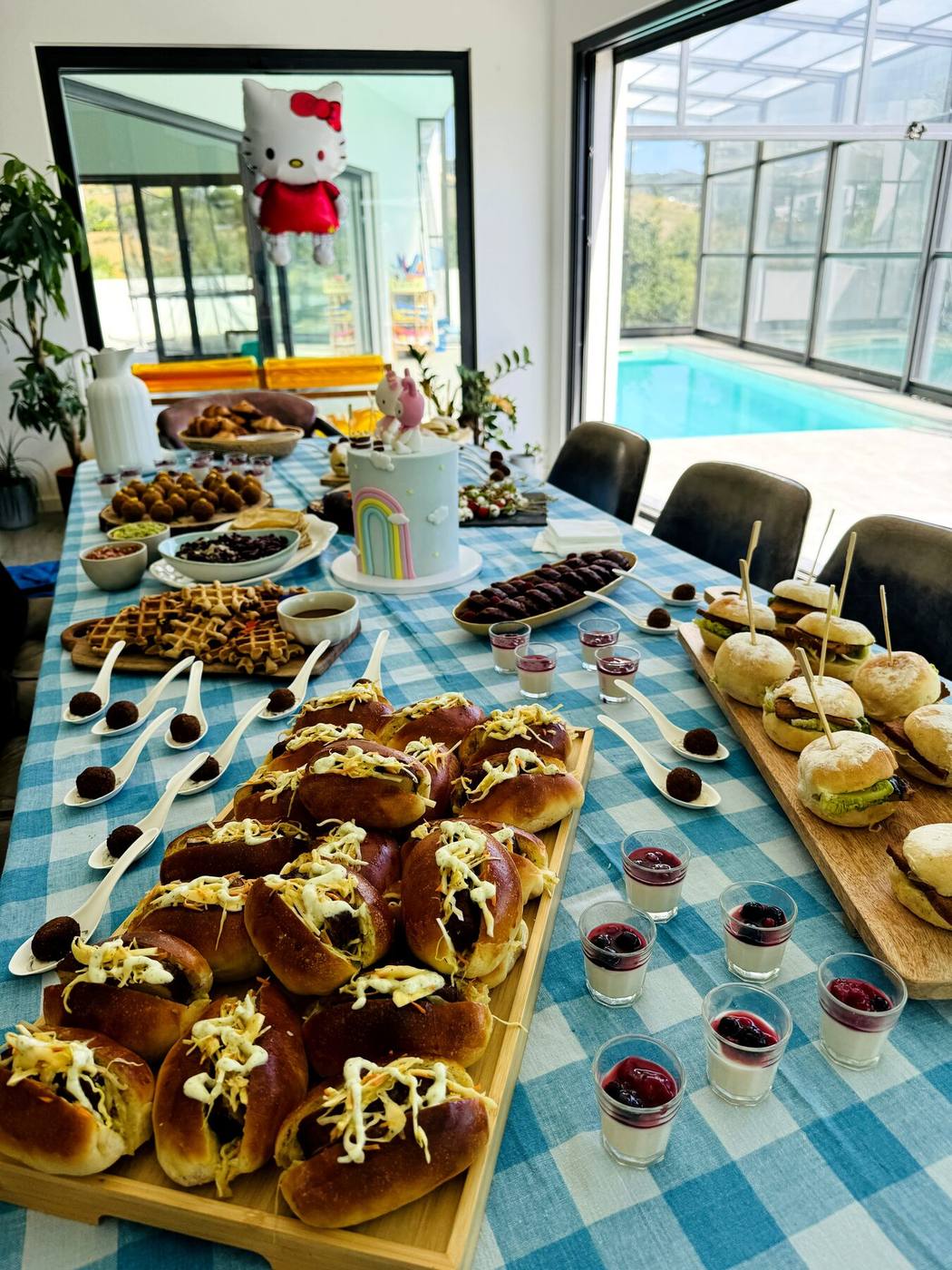 Mesa de festa privada junto à piscina com waffles, bolo e mini sandes